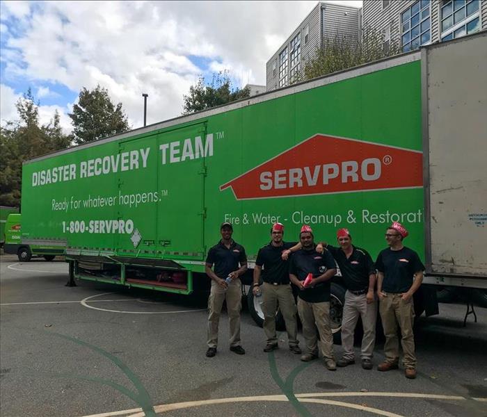 SERVPRO techs standing in front of our trailer parked in the parking lot