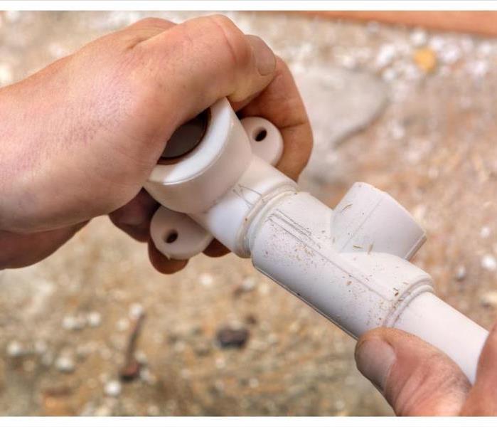 The plumber in Nashville connects parts of the plastic water pipe using fittings, hands close-up.